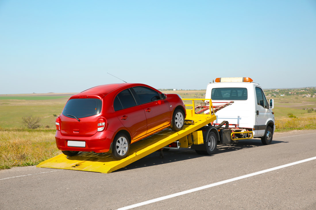 Red car being towed by a tow truck.